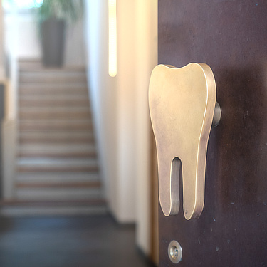 Die Eingangstür der Zahnarztpraxis Dr. Hannig in Kandel hat einen zahnförmigen Türknauf.